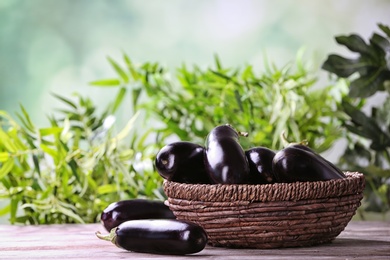 Photo of Bowl with ripe eggplants on table against blurred background