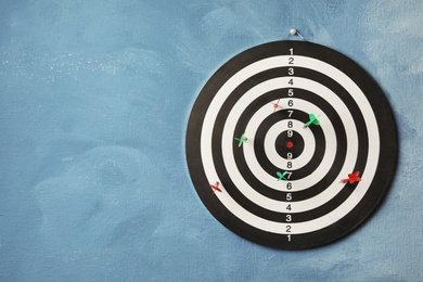 Arrows hitting dart board on blue wall. Space for text