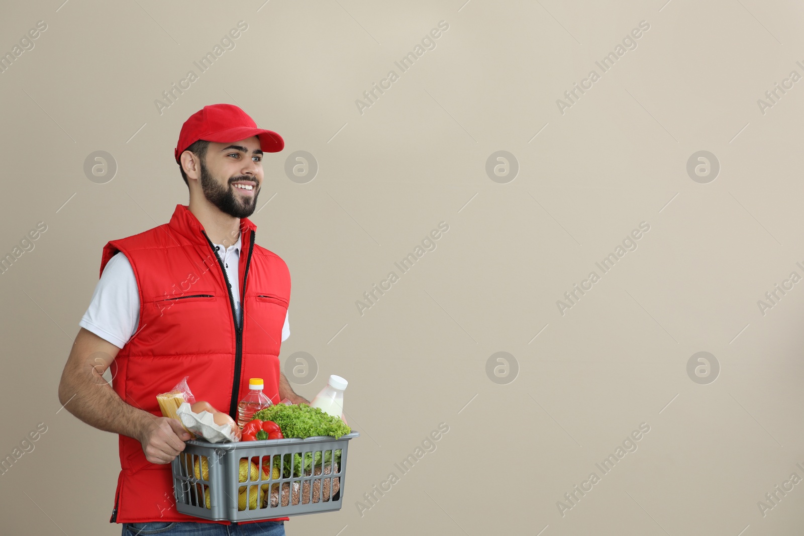 Photo of Man holding basket with fresh products on color background, space for text. Food delivery service