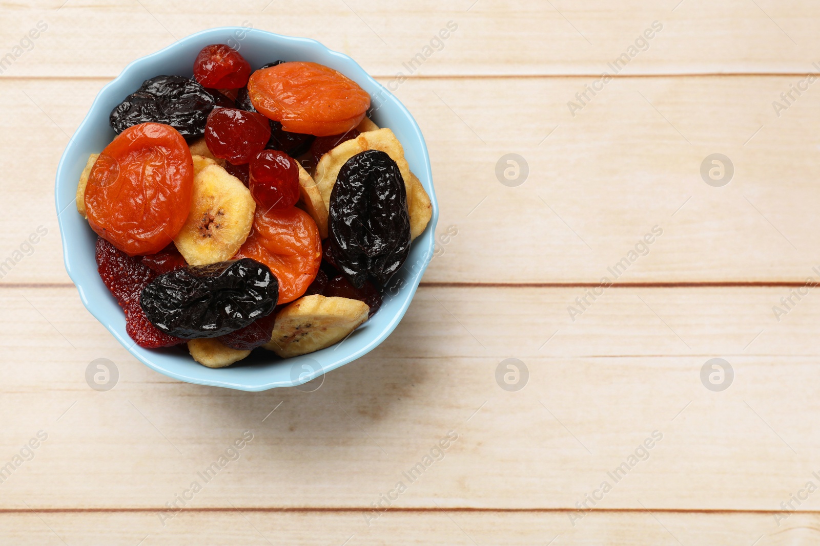 Photo of Mix of delicious dried fruits on white wooden table, top view. Space for text