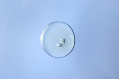 Drop of hydrophilic oil on light blue background, top view