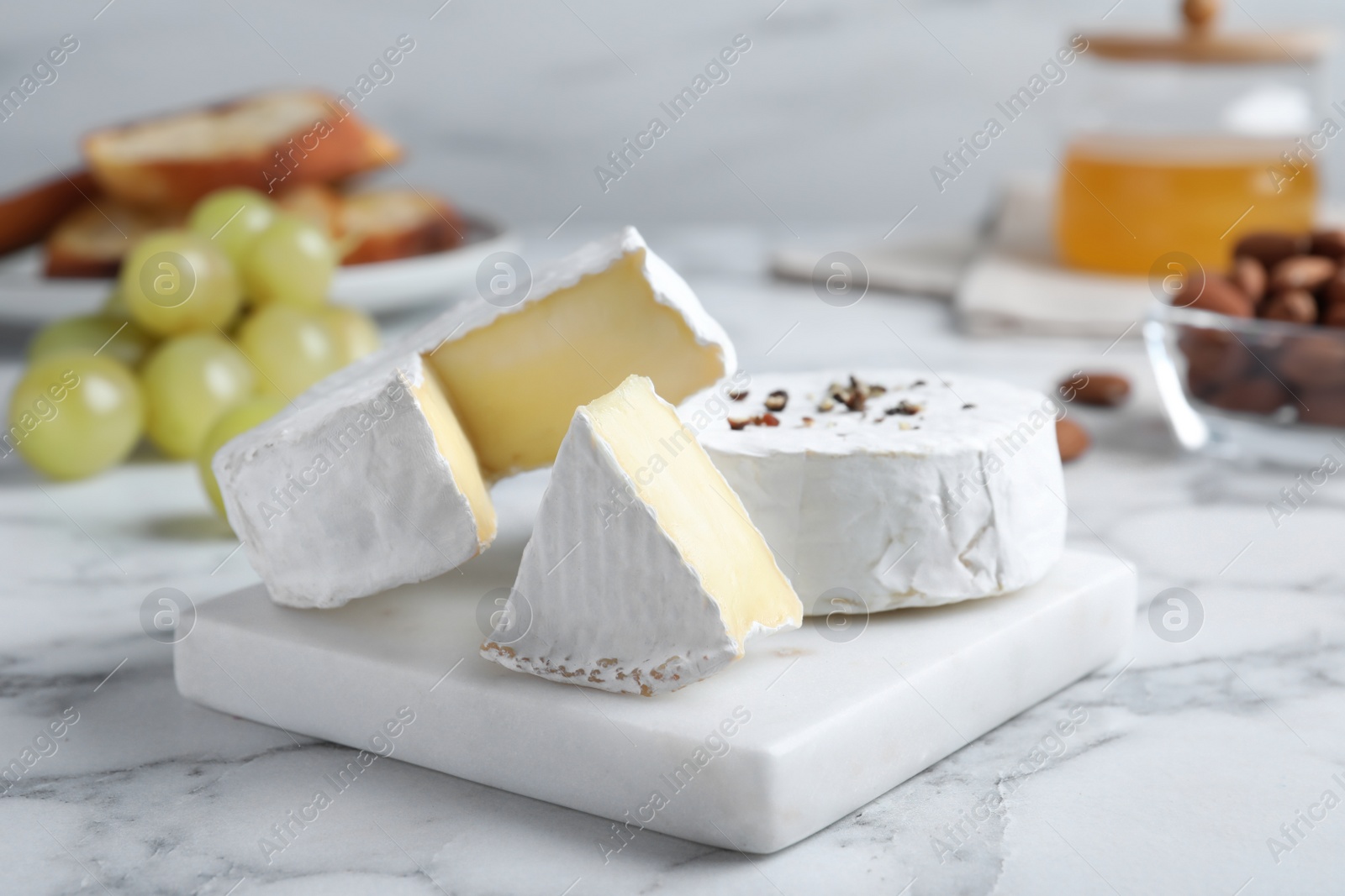 Photo of Tasty brie cheese on white marble table