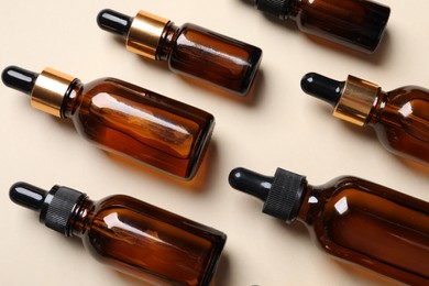 Many bottles with face serums on beige background, above view