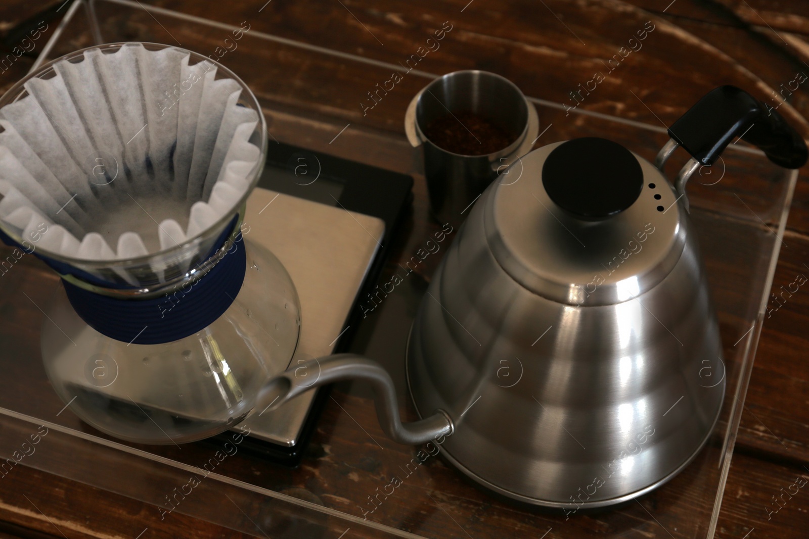 Photo of Cup with coffee, wave dripper and kettle on wooden table in cafe