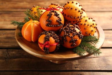 Pomander balls made of fresh tangerines and cloves on wooden table