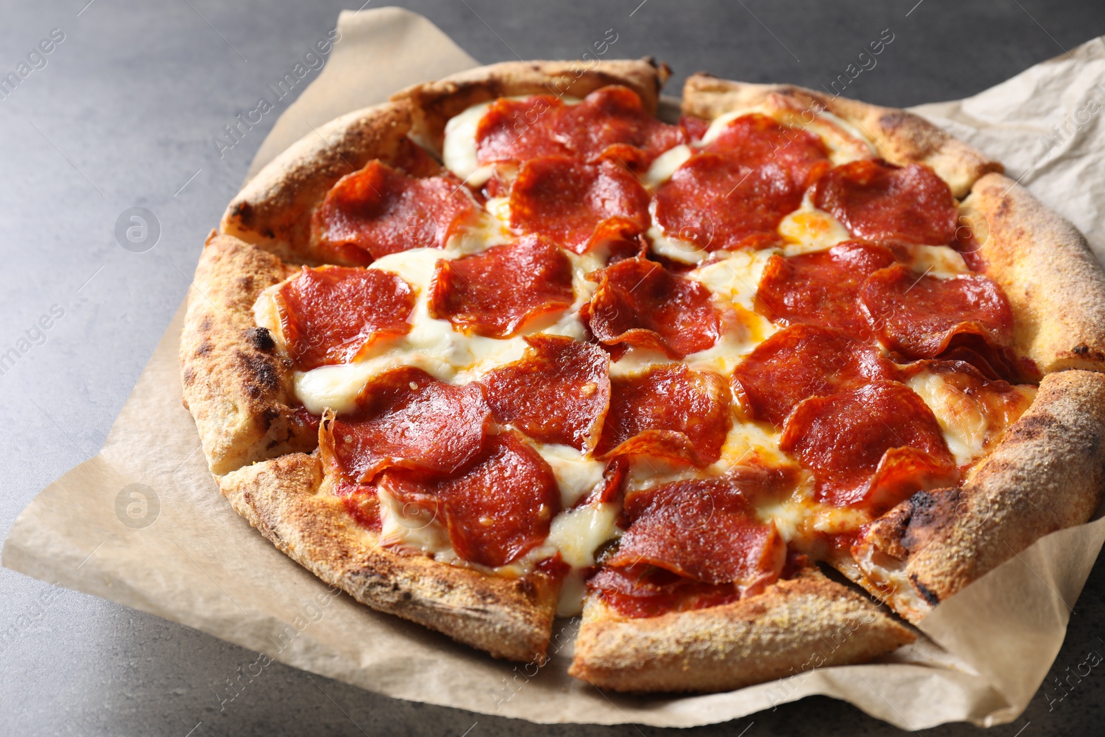 Photo of Tasty hot pepperoni pizza on grey table