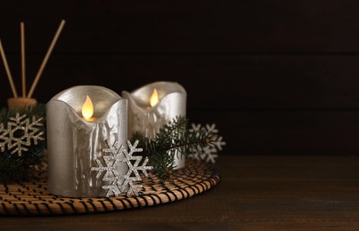 Photo of Decorative LED candles and snowflakes on wooden table, space for text