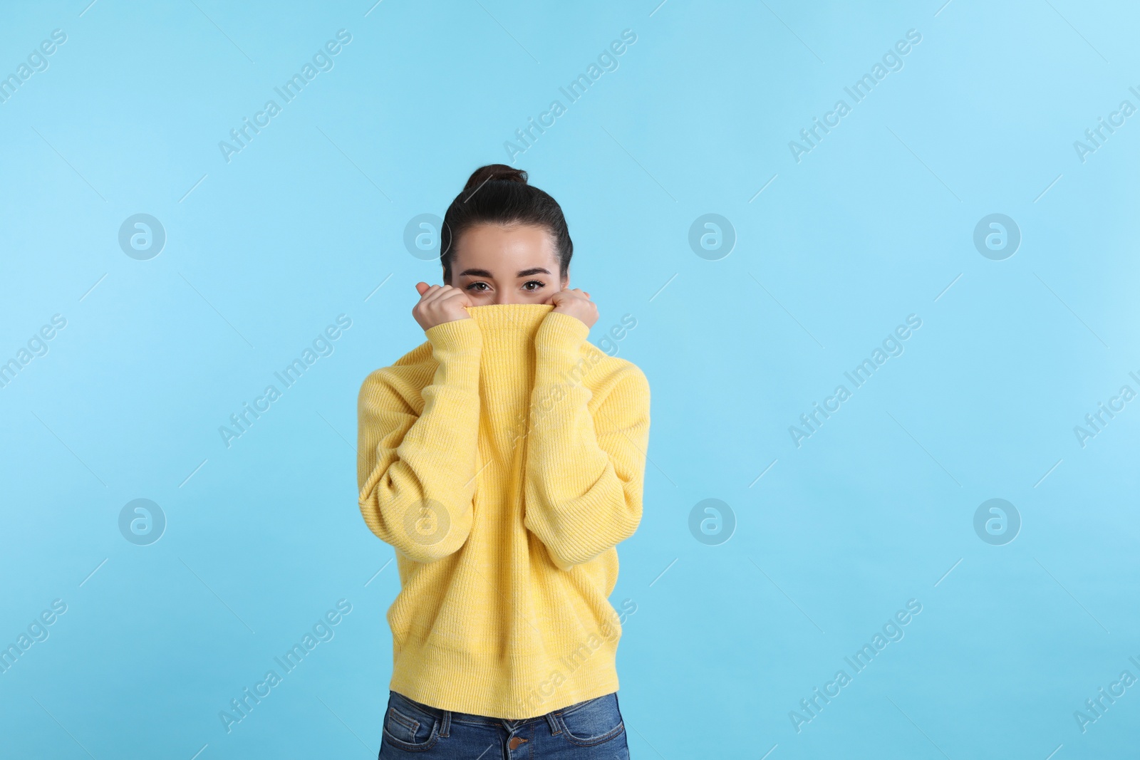 Photo of Beautiful young woman wearing yellow warm sweater on light blue background