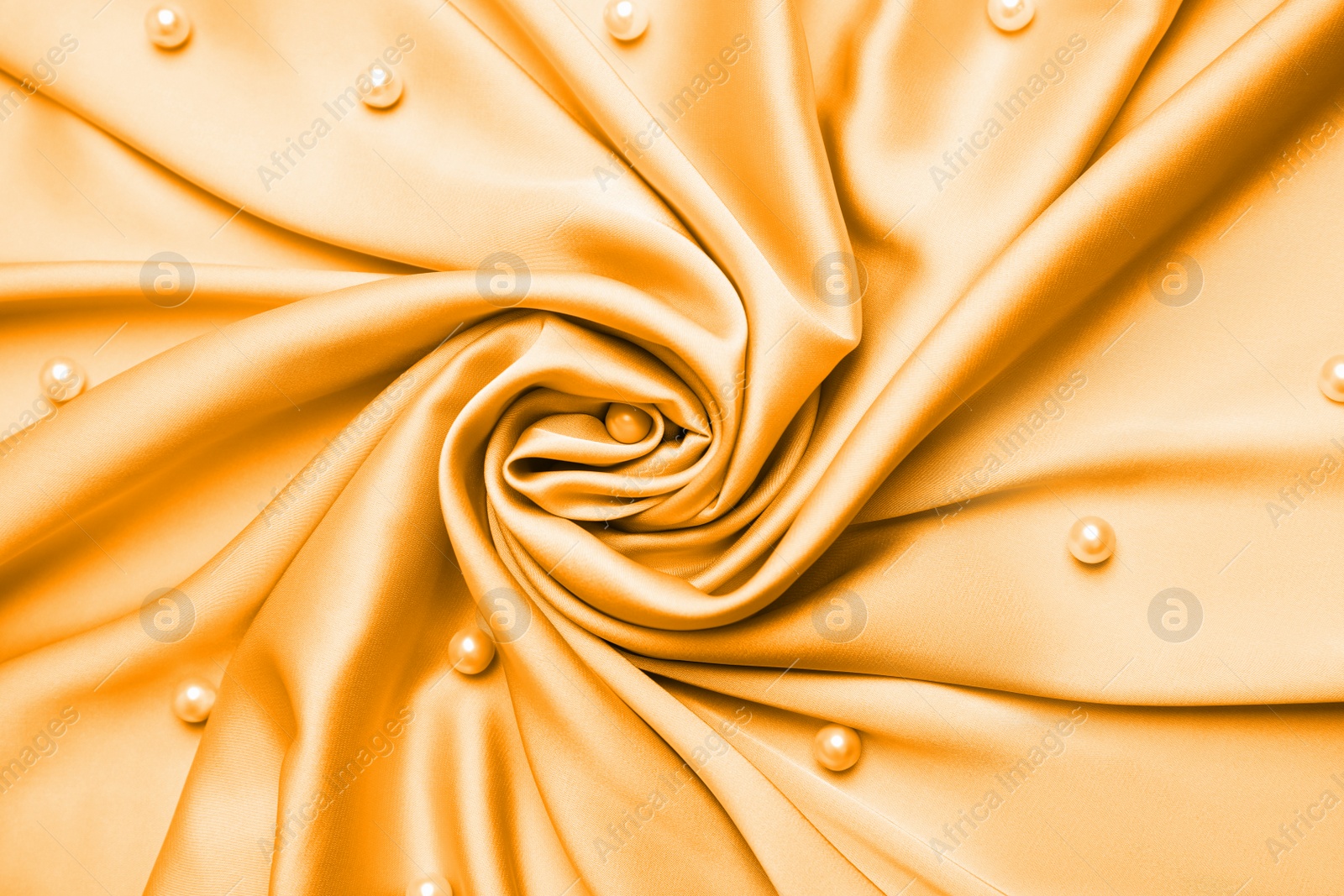 Image of Many beautiful pearls on delicate light orange silk, flat lay