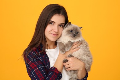 Photo of Woman with her cute cat on orange background