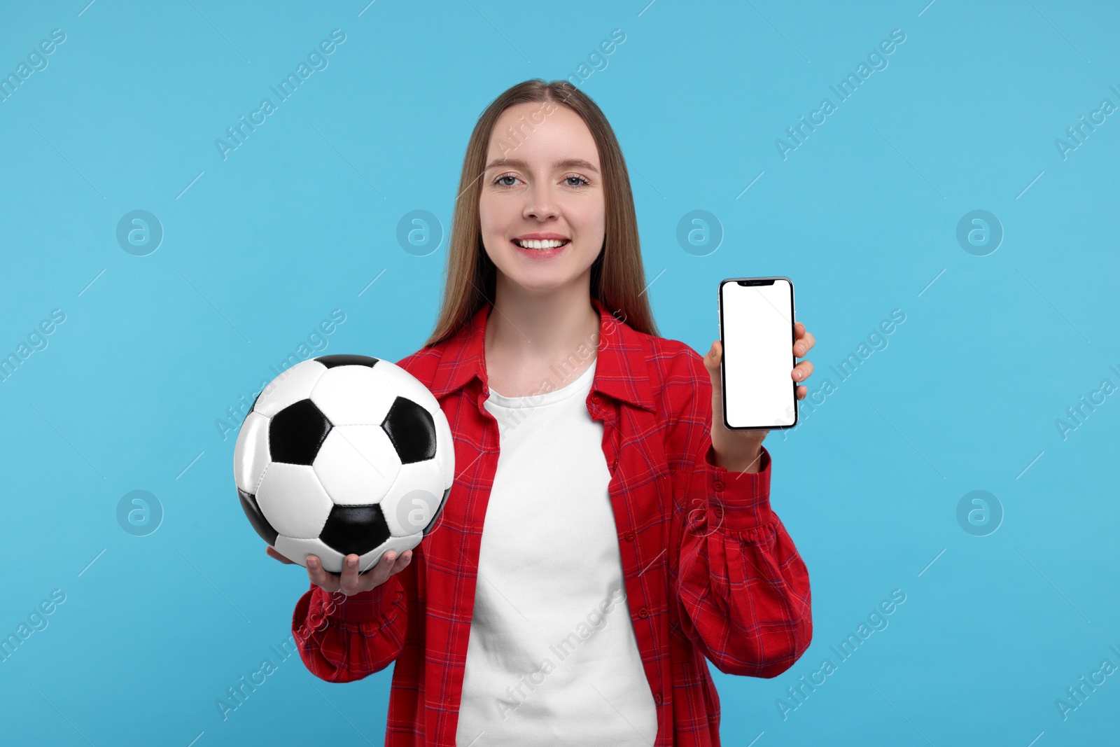 Photo of Happy sports fan with ball and smartphone on light blue background