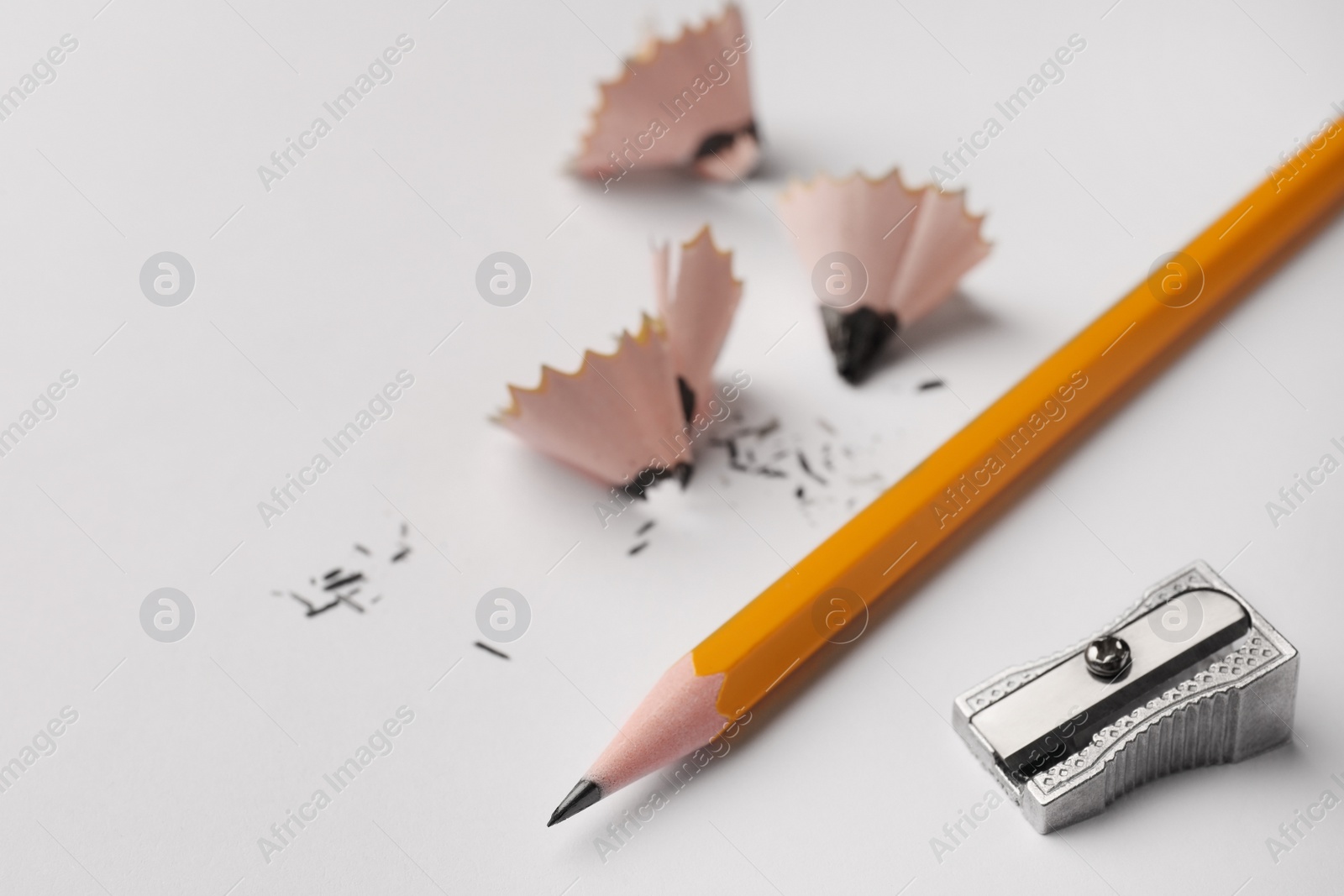 Photo of Graphite pencil, shavings and sharpener on white background, closeup