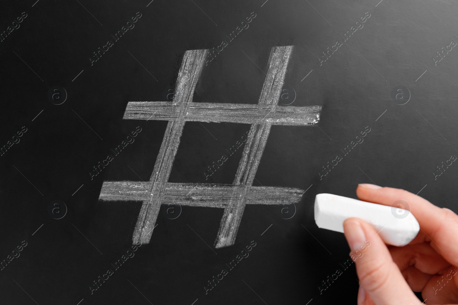 Photo of Woman drawing hashtag symbol with chalk on blackboard, closeup