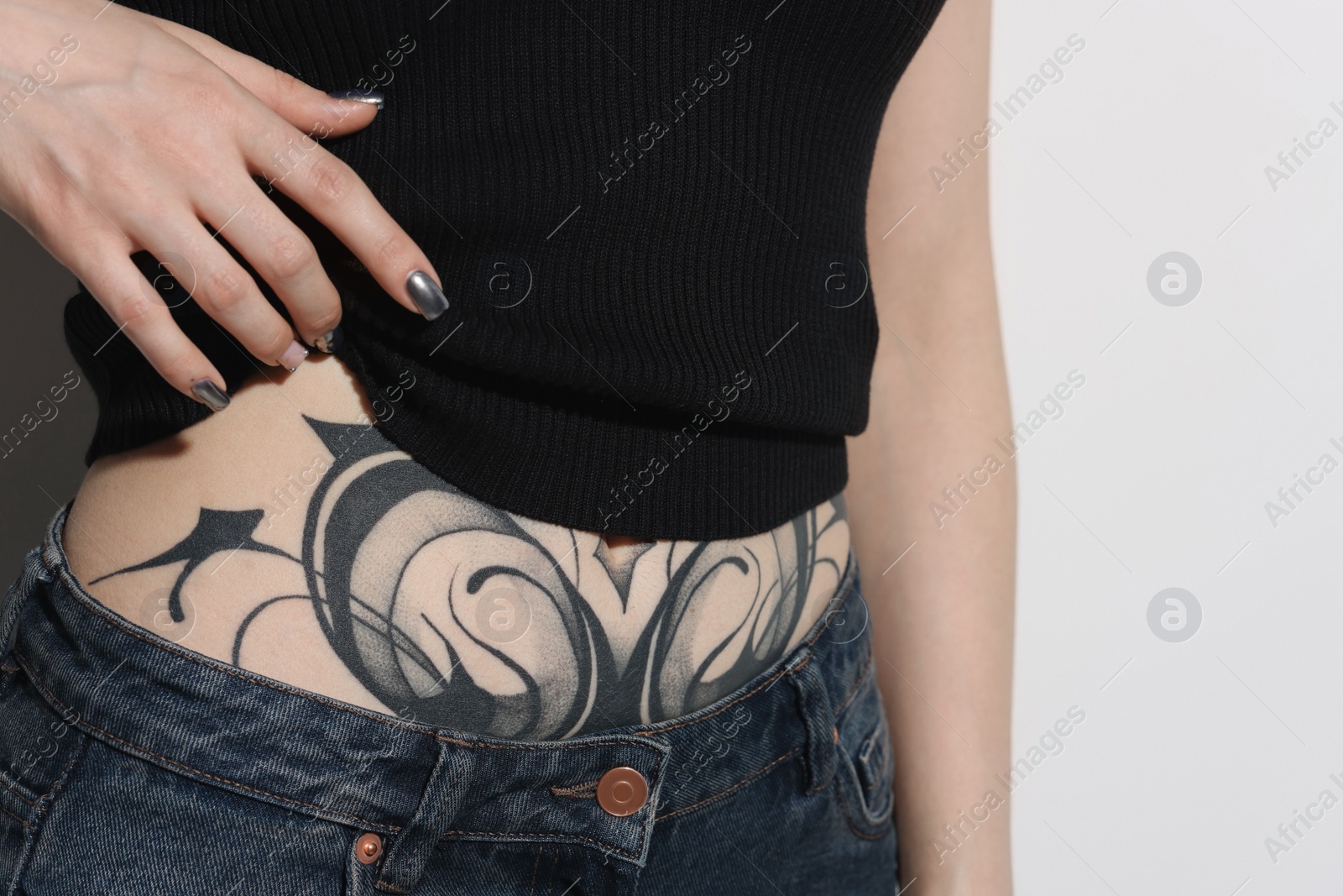 Photo of Woman with cool tattoos on light background, closeup