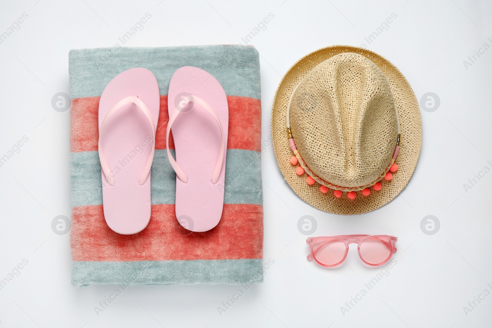 Photo of Beach towel, flip flops, hat and sunglasses on white background, flat lay