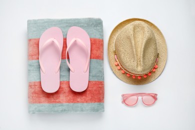 Photo of Beach towel, flip flops, hat and sunglasses on white background, flat lay