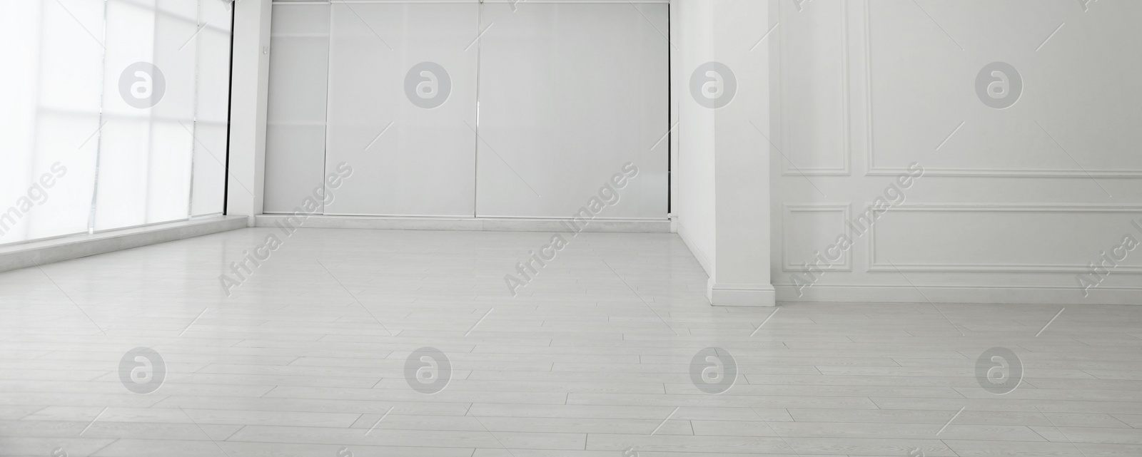 Photo of Empty room with white walls and laminated flooring