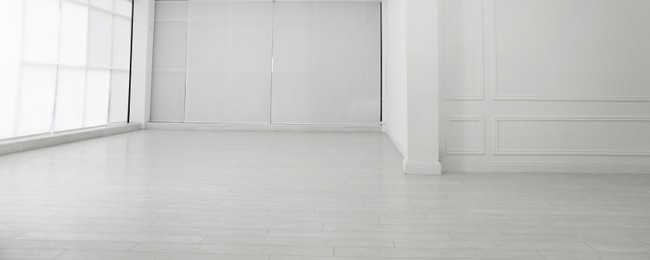 Photo of Empty room with white walls and laminated flooring