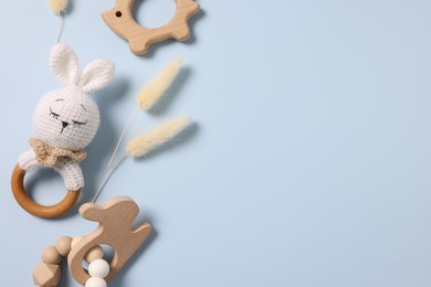 Photo of Baby accessories. Rattle, teethers and dry spikes on light blue background, flat lay. Space for text