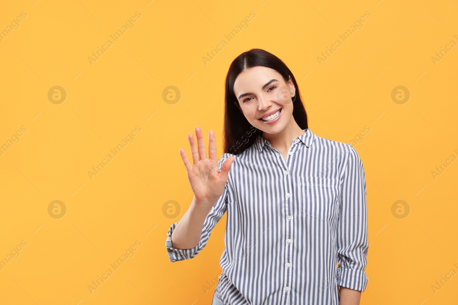 Photo of Happy woman giving high five on orange background, space for text