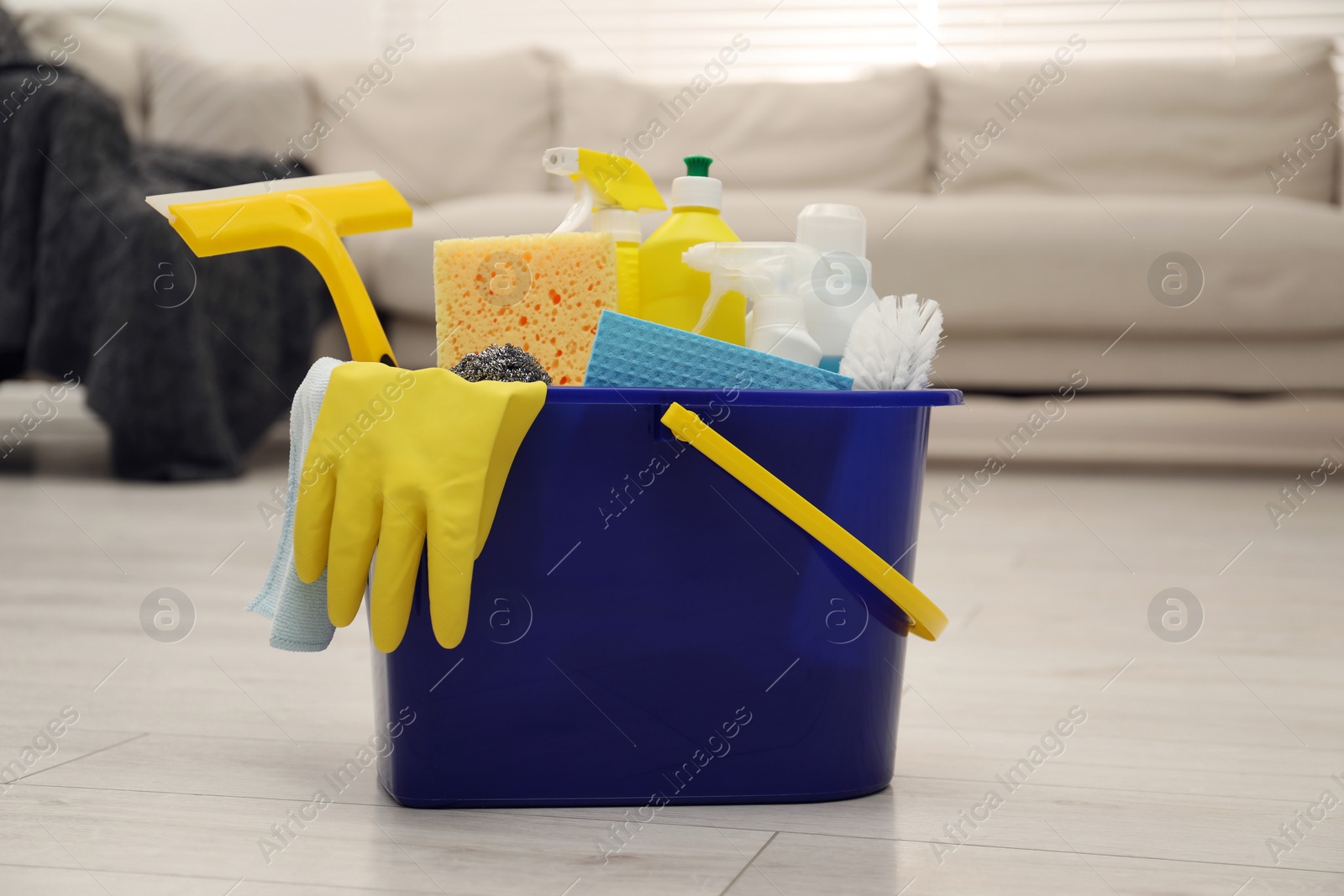 Photo of Different cleaning supplies in bucket on floor at home