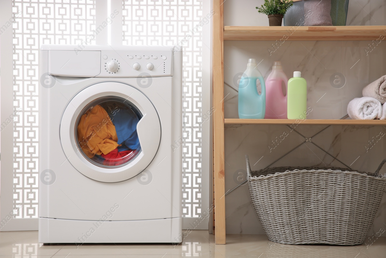 Photo of Modern washing machine with clothes in bathroom