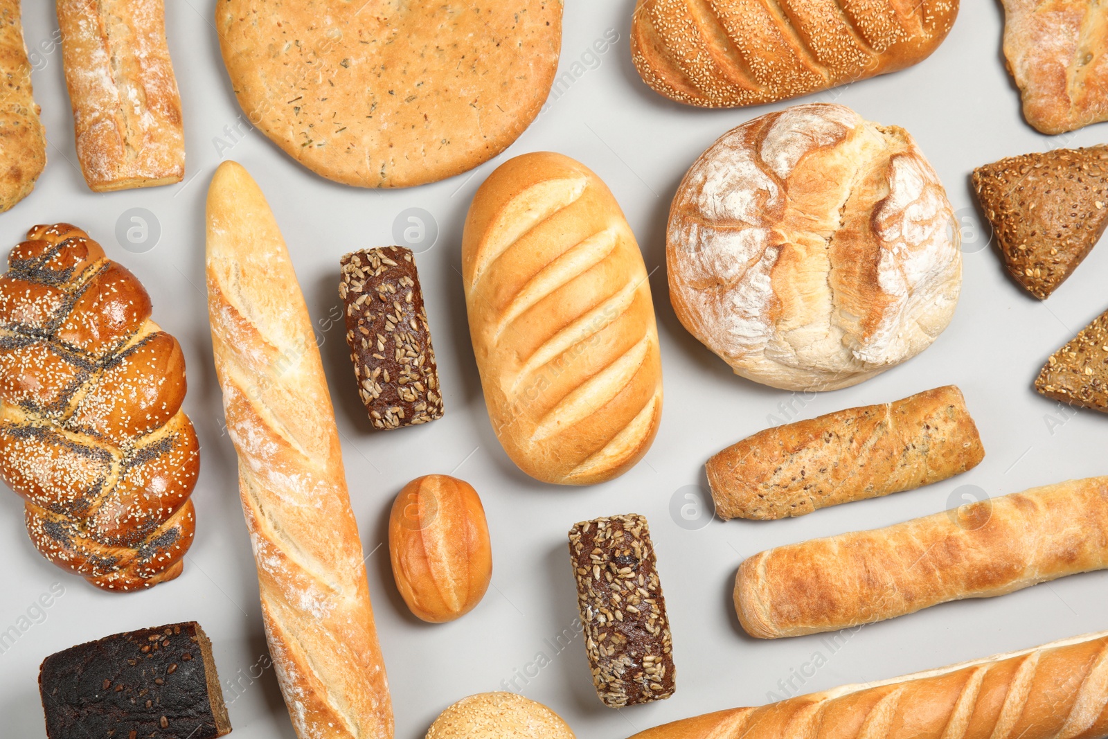 Photo of Different kinds of fresh bread on light background, flat lay