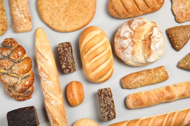 Different kinds of fresh bread on light background, flat lay
