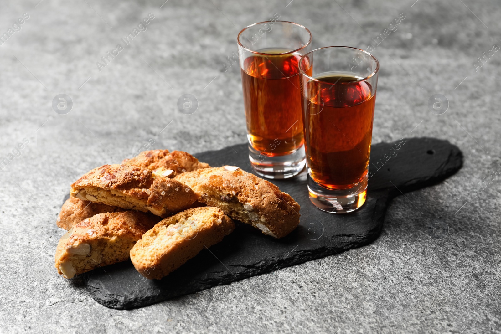 Photo of Tasty cantucci and glasses of liqueur on grey table. Traditional Italian almond biscuits