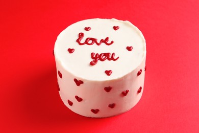 Photo of Bento cake with text Love You on red table. St. Valentine's day surprise