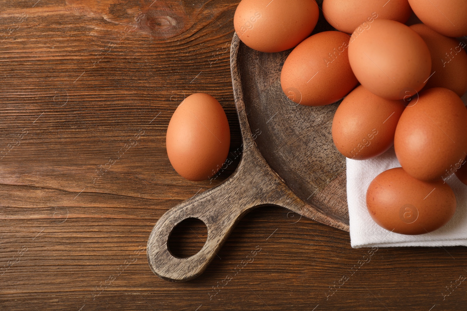 Photo of Raw brown chicken eggs on wooden table, flat lay. Space for text