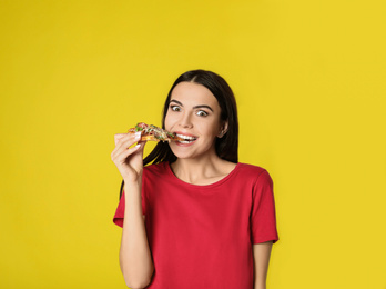 Photo of Emotional woman eating tasty pizza on yellow background