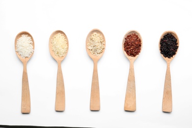 Photo of Spoons with different types of uncooked rice on white background, top view