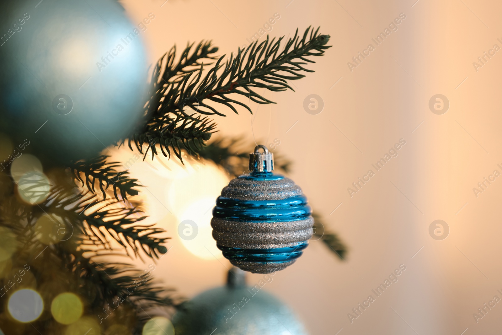 Photo of Christmas tree decorated with light blue festive balls on blurred background, closeup. Space for text