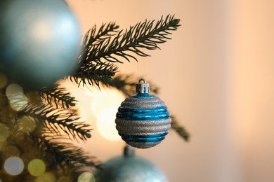 Christmas tree decorated with light blue festive balls on blurred background, closeup. Space for text