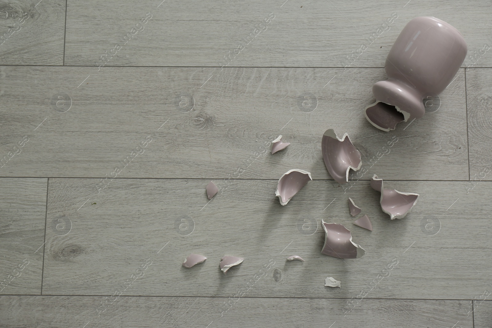 Photo of Broken pink ceramic vase on wooden floor, flat lay. Space for text