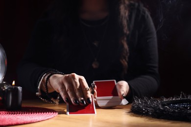 Photo of Soothsayer predicting future with cards at table indoors, closeup