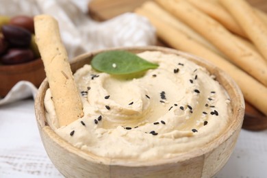 Photo of Delicious hummus with grissini stick on white wooden table, closeup