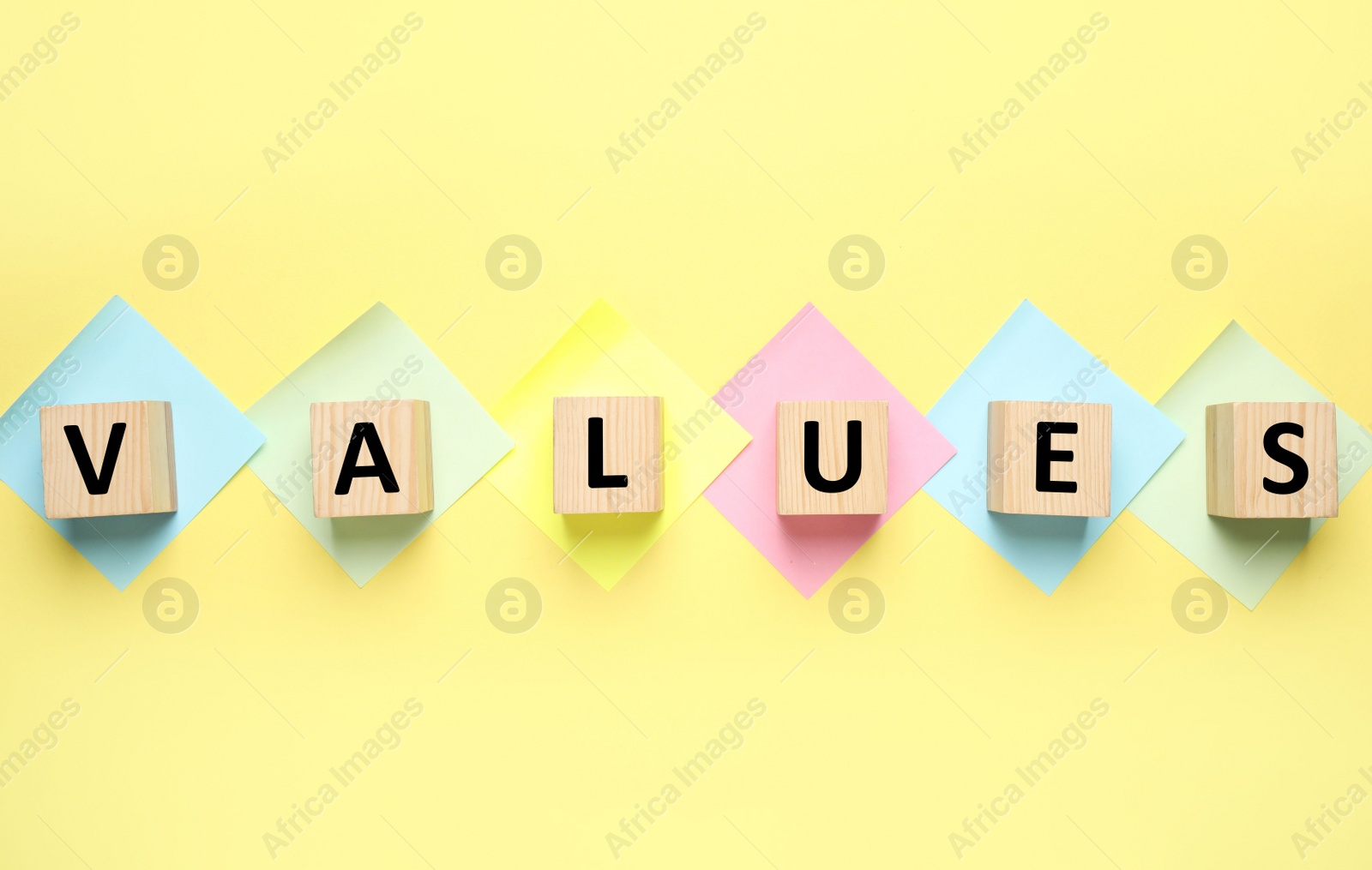 Photo of Wooden cubes with word VALUES on yellow background, flat lay