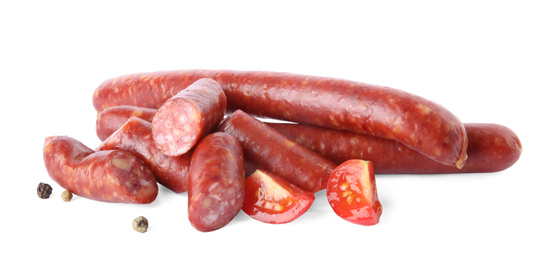 Photo of Delicious smoked sausages with tomato and pepper on white background