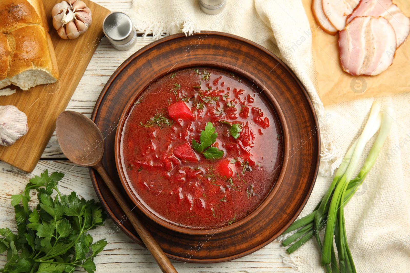 Photo of Stylish brown clay bowl with Ukrainian borsch served on white wooden table, flat lay