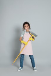 African American woman with yellow broom on grey background