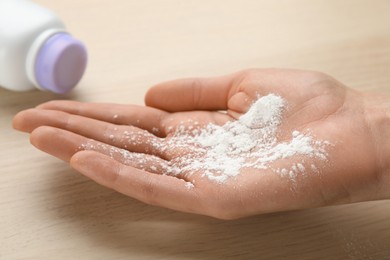 Woman with dusting powder at wooden table, closeup