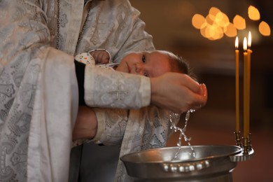 Photo of Priest baptizing adorable baby in church, closeup