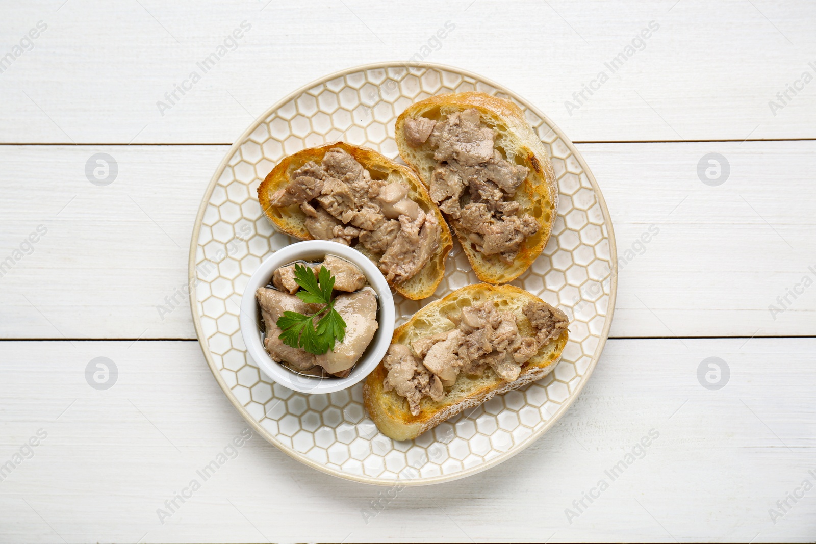 Photo of Tasty sandwiches with cod liver and parsley on white wooden table, top view