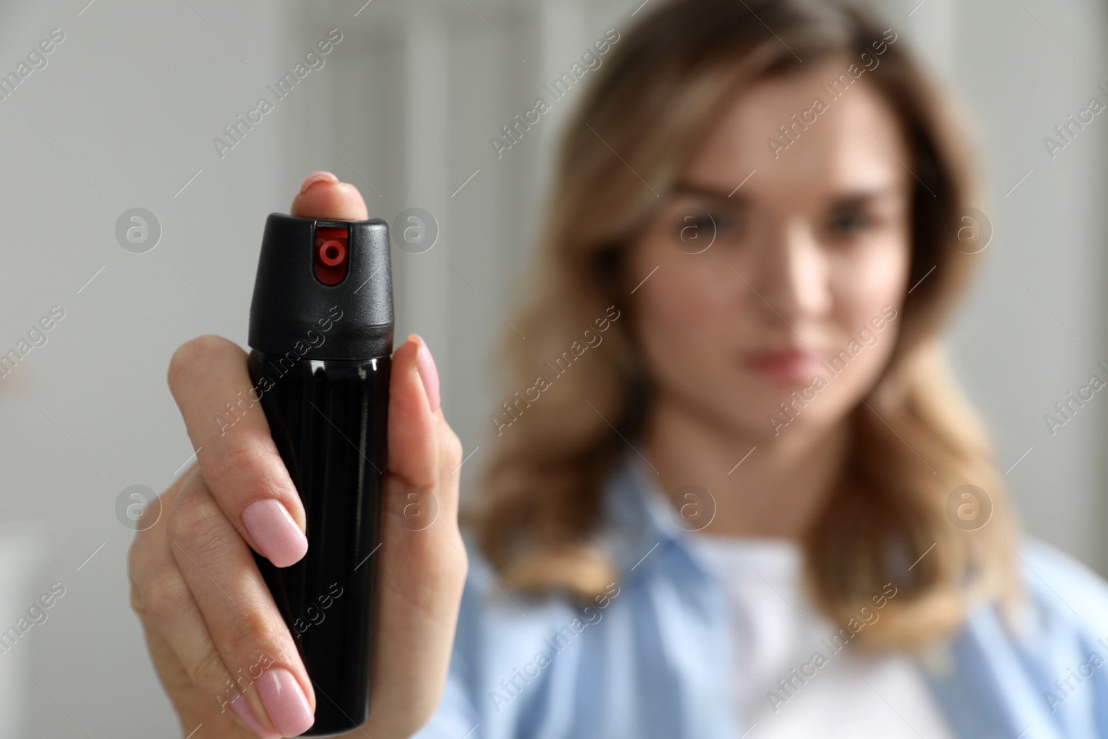 Photo of Young woman using pepper spray at home, focus on hand