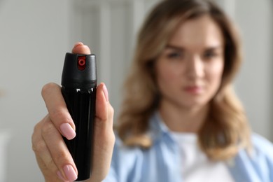 Photo of Young woman using pepper spray at home, focus on hand