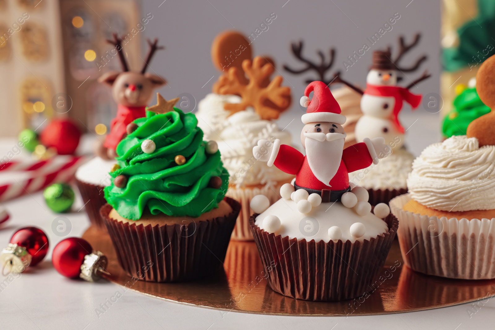 Photo of Different beautiful Christmas cupcakes and baubles on white table
