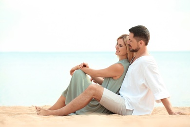 Happy romantic couple sitting together on beach