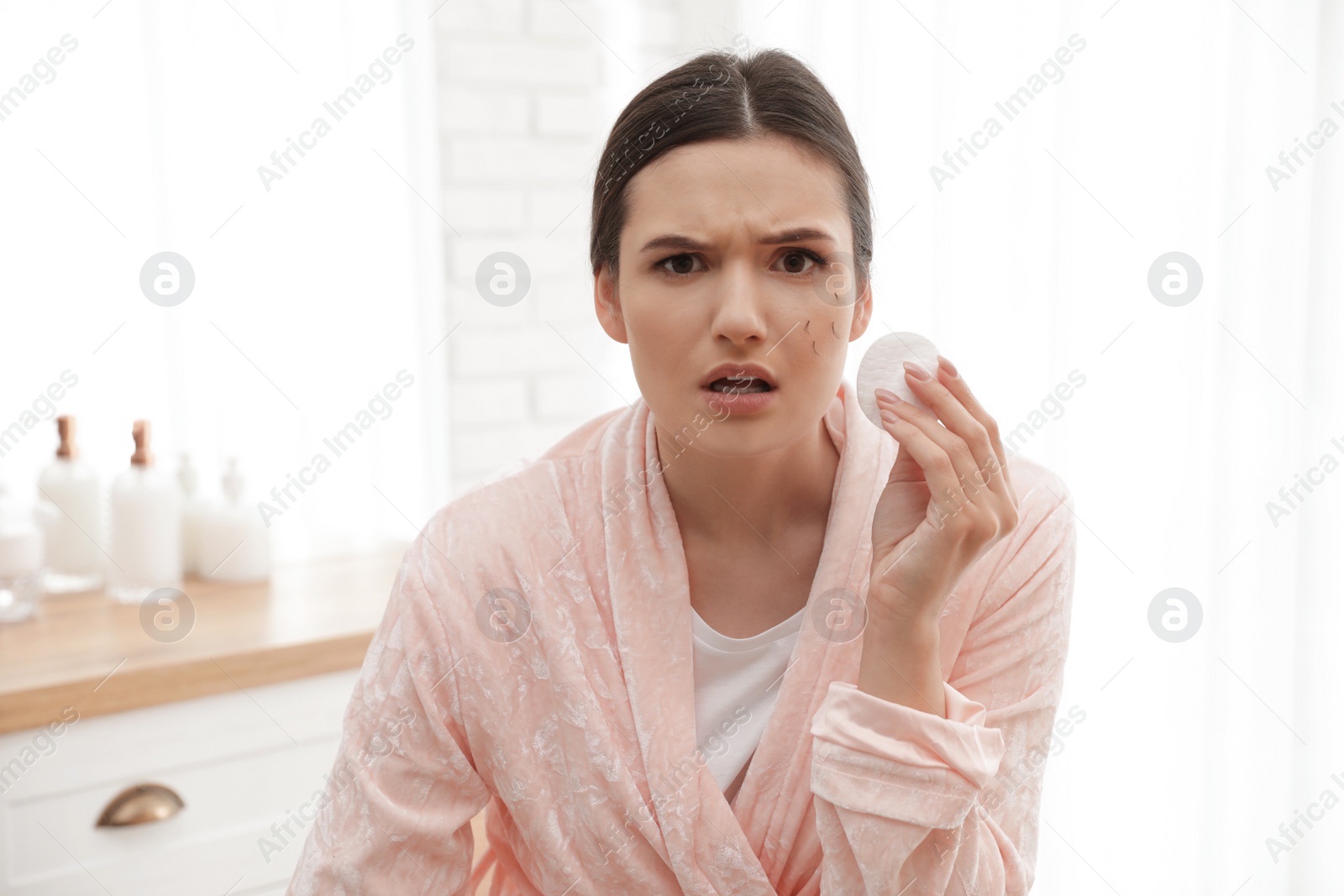 Photo of Beautiful woman with fallen eyelashes holding cotton pad indoors